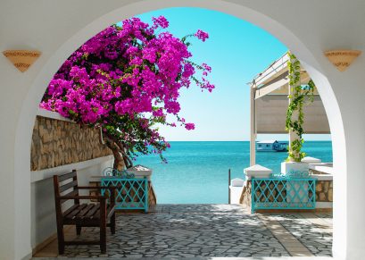 view-blue-sea-tunisia-through-white-archway-with-pink-blooming-flowers-foreground-distance-house-water